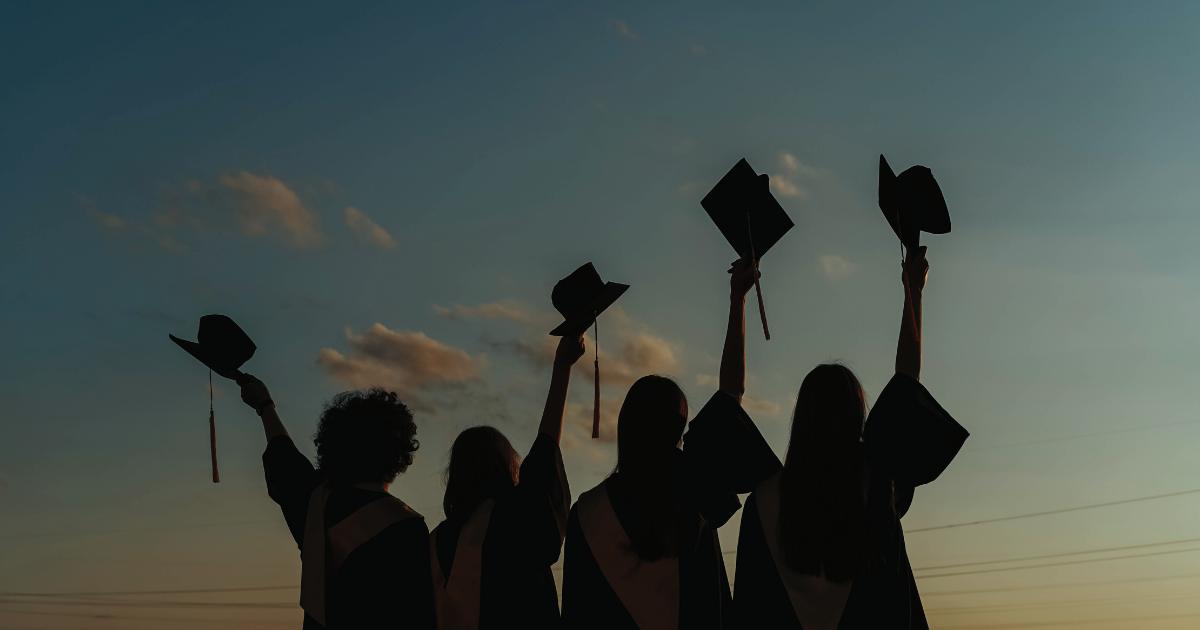 Photo of graduates lifting graduation caps in air